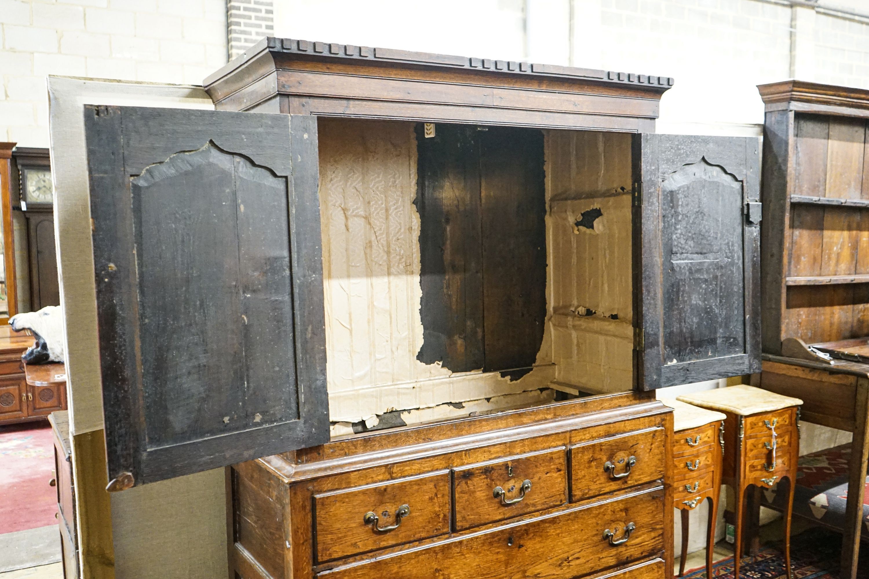 A George III oak press cupboard, with moulded cornice and two panelled doors over five drawers, width 122cm, depth 52cm, height 183cm